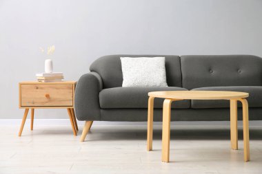 Rahat bir kanepe ve gri duvarın yanındaki masalar.