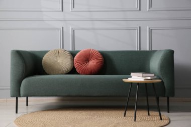 Rahat bir kanepe ve gri duvarın yanındaki yan masa.