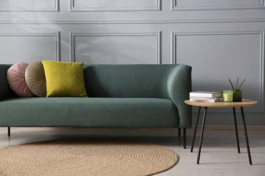 Rahat bir kanepe ve gri duvarın yanındaki yan masa.