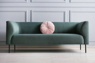 Gri duvarın yanındaki yastıklı şık kanepe.