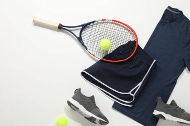 Tenis raketi, toplar, spor ayakkabıları ve arka planda spor giysileri, düz yatak. Metin için boşluk