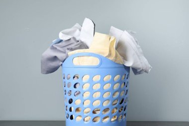 Çamaşır dolu plastik sepet gri arka planda.