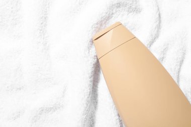 Yumuşak havluyla şampuan şişesinde, üst manzara. Metin için boşluk