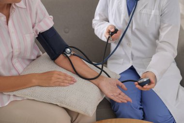 Doktor, hastanın kan basıncını ölçüyor.