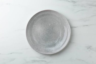 Beyaz mermer masada şık bir tabak, üst görünüm.