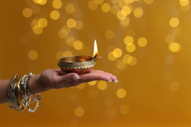 Diwali kutlaması. Elinde yanan diya lambası tutan bir kadın. Arka planda bulanık ışıklar var. Yakın plan. Metin için boşluk