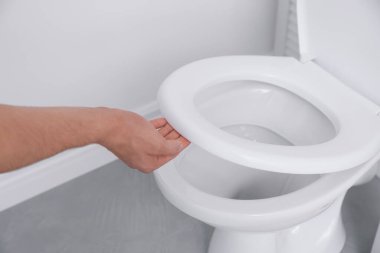 Adam tuvalette klozet kapağını kapatıyor.