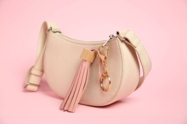 Pembe arka planda deri anahtarlıklı çanta, yakın plan.