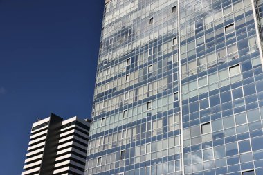 Mavi gökyüzüne karşı birçok penceresi olan modern binanın dış görünüşü, düşük açı görünümü