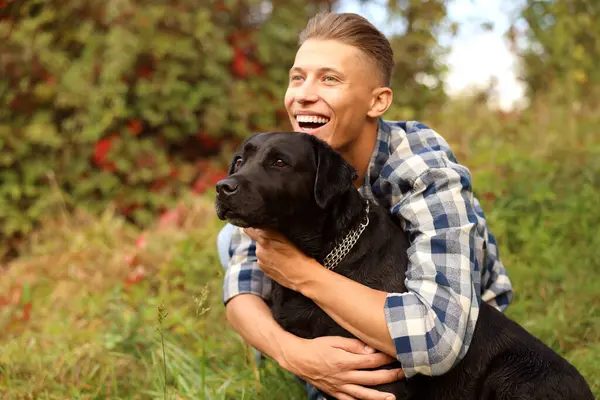 Gülümseyen adam güz gününde dışarıda sevimli köpeğe sarılıyor. Metin için boşluk