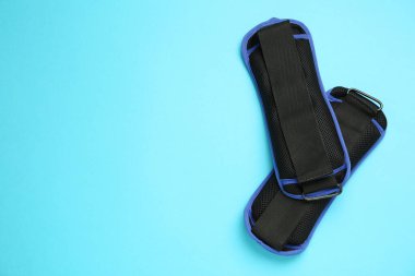 Açık mavi arka planda şık ayak bileği ağırlıkları, düz yatış. Metin için boşluk