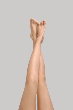 Gri arka planda pürüzsüz bacakları olan kadın, yakın plan.