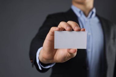 Gri arka planda boş bir kartvizit tutan adam, yakın plan. Tasarım için model