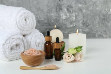 Beyaz masa üzerinde kozmetik ürünleri ve havlularla spa kompozisyonu
