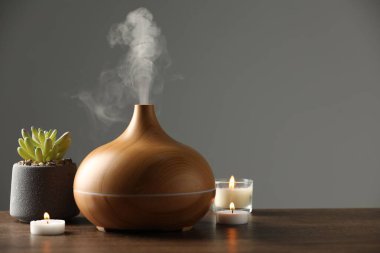 Aroma yağı yayıcı, ağaç masa üzerinde bitki ve yanan mumlar, metin için alan