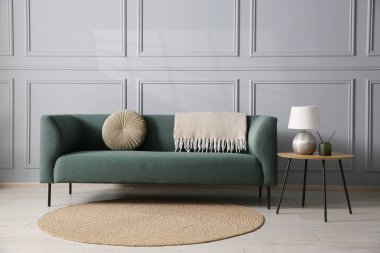 Rahat bir kanepe ve gri duvarın yanındaki yan masa.