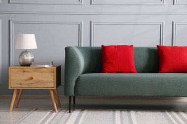 Rahat bir kanepe ve gri duvarın yanındaki yan masa.