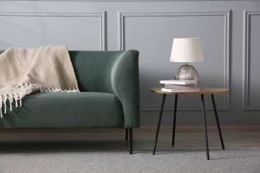 Rahat bir kanepe ve gri duvarın yanındaki yan masa.