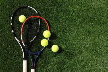 Tenis raketleri ve toplar yeşil yapay çimlerde, düz yerde. Metin için boşluk