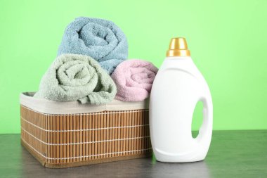 Çamaşır deterjanı şişede ve havlular gri masada.