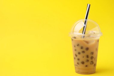 Sarı arka planda plastik fincanlarda lezzetli sütlü çay, metin için yer