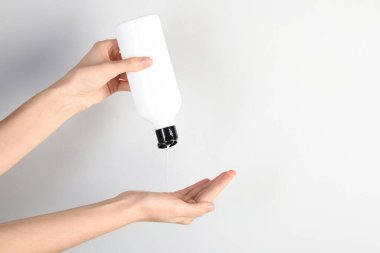 Gri arka plana şampuan döken bir kadın, yakın plan. Metin için boşluk