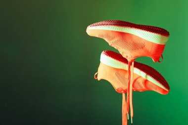 Koyu yeşil arka plana karşı havada şık spor ayakkabılar, metin için boşluk