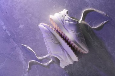 Neon ışıklarda mermer arka planda şık bir çift spor ayakkabı, üst manzara.