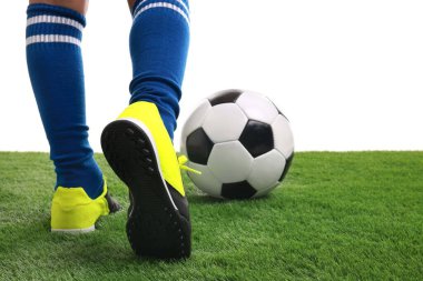 Beyazların arka planına karşı suni çimlerde futbol oynayan çocuk, yakın plan.