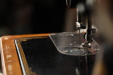 Bulanık arkaplanda ipliği olan dikiş makinesi, makro görünüm. Metin için boşluk