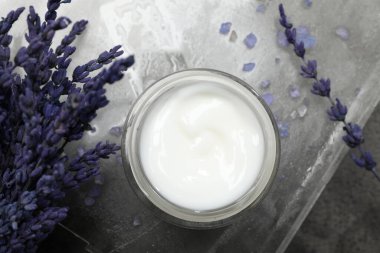 Gri masa üzerinde kozmetik ürün kavanozu ve lavanta çiçekleri içeren spa kompozisyonu