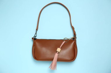 Açık mavi arkaplanda pembe deri anahtarlıklı çanta, üst görünümde.