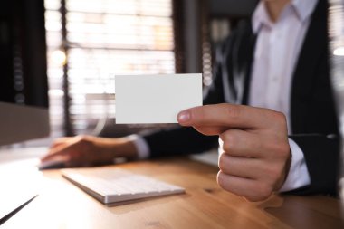 Ofiste bilgisayarla çalışırken elinde boş bir kartvizit tutan adam, yakın plan. Tasarım için model
