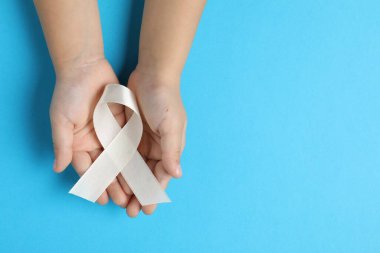 Açık mavi arka planda beyaz kurdeleli çocuk, yazı için üst görünüm ve boşluk. Kemik kanseri ve akciğer hastalığı farkındalığı