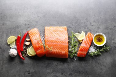 Gri masada taze somon, limon ve baharat parçaları.