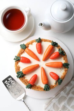 Lezzetli havuçlu kek, sunucu ve çay beyaz masada, üst manzara.