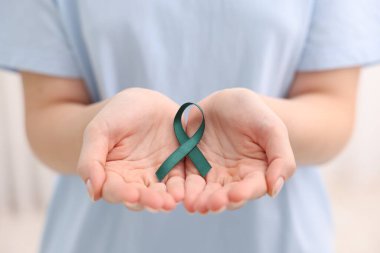 Woman with teal ribbon on light background, closeup. Ovarian cancer and gynecological disorders awareness clipart