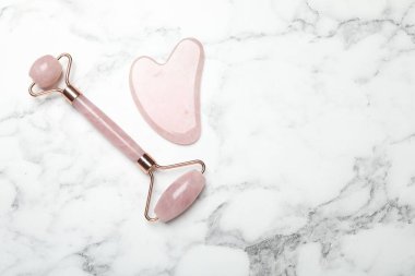 Beyaz mermer zemin üzerinde yüz silindiri ve gua sha aracı, düz yatıyordu. Metin için boşluk