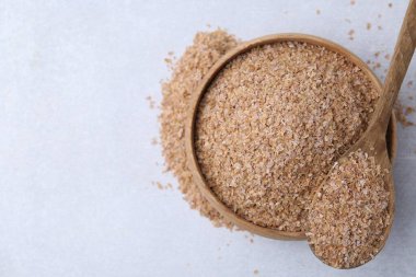 Kase içinde karabuğday kepeği ve açık gri masada kaşık, üst manzara. Metin için boşluk