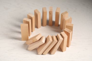Domino etkisi. Tahta bloklar beyaz masaya düşüyor, yakın plan.