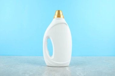 Çamaşır deterjanı şişede gri mermer masada açık mavi arka planda