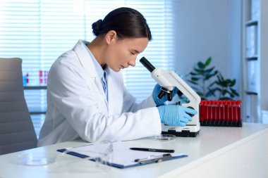 Laboratuvar testi. Doktor, mikroskopla kapalı bir masada çalışıyor.