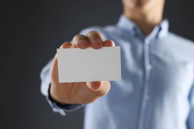 Gri arka planda boş bir kartvizit tutan adam, yakın plan. Tasarım için model