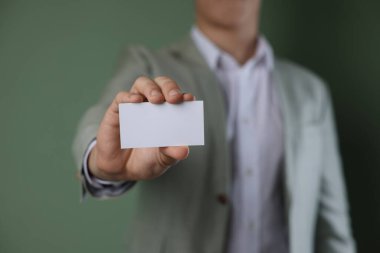 Yeşil arka planda boş kartviziti olan bir adam, yakın plan. Tasarım için model