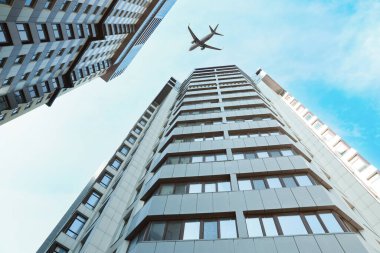 Şehirdeki binaların üzerinden uçan uçak, alçak açı.