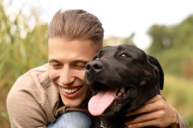 Açık havada sevimli bir köpekle gülümseyen adamın portresi.