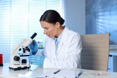 Laboratuvar testi. Doktor, içeride mikroskopla çalışırken cam kaydırağına kan damlatıyor.