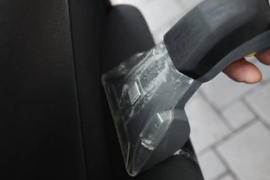 Arabanın kapısını elektrikli süpürgeyle temizleyen adam, yakın plan.