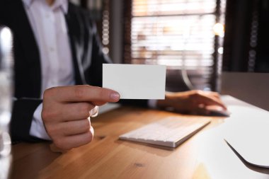 Ofiste bilgisayarla çalışırken elinde boş bir kartvizit tutan adam, yakın plan. Tasarım için model