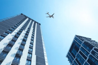 Şehirdeki binaların üzerinden uçan uçak, alçak açı.